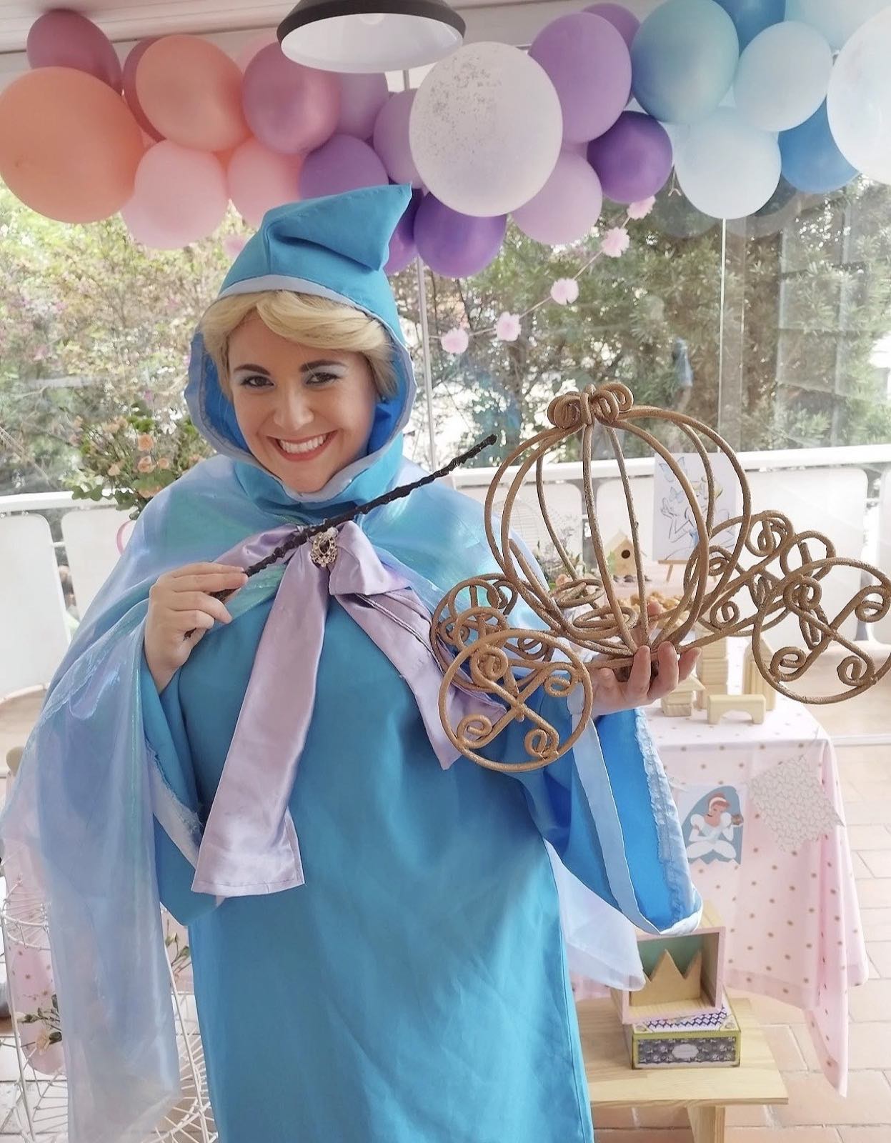 Fada Madrinha de capa azul, com varinha e a carruagem dourada nas mãos