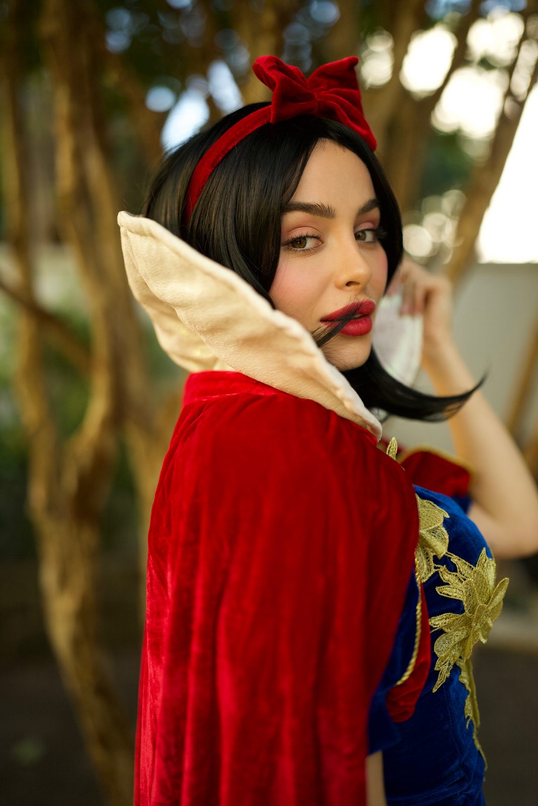 Retrato da Princesa da Neve com laço vermelho no cabelo e capa vermelha, ao fim da tarde